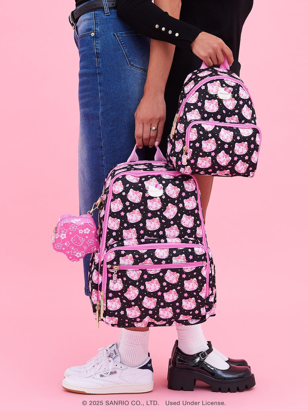 Person holding a JuJube bag with cherry blossom pattern against a pink background