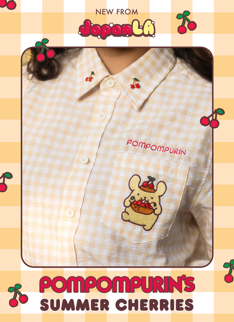 A close-up of a person wearing a light beige and white gingham button-up shirt with cherry embroidery and a cartoon bear patch on the pocket. The image has a decorative border with cherries and text reading 'NEW FROM JapanLai' and 'Pompompurin's Summer Cherries'.