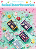 A flat-lay product display of Sanrio Originals 'heisei hearts series' cute zippered pouches and charms scattered on a pastel pink and mint green background with decorative hearts and gems.