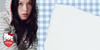 A person wearing a light gray and white striped hoodie with red trim and a Hello Kitty patch, posed against a blue-and-white gingham background with a large torn-paper graphic on the right. A Hello Kitty heart logo is visible in the lower left.