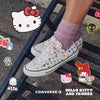 Converse x Hello Kitty and Friends shoes with cartoon character stickers on a concrete floor.