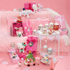 Pink-themed room with Hello Kitty decor, including toys, mugs, and gift boxes on a pink couch.