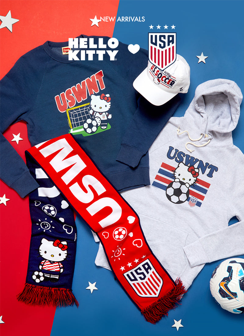 USWNT Hello Kitty merchandise including a sweatshirt, cap, scarf, and hoodie on a red and blue background.