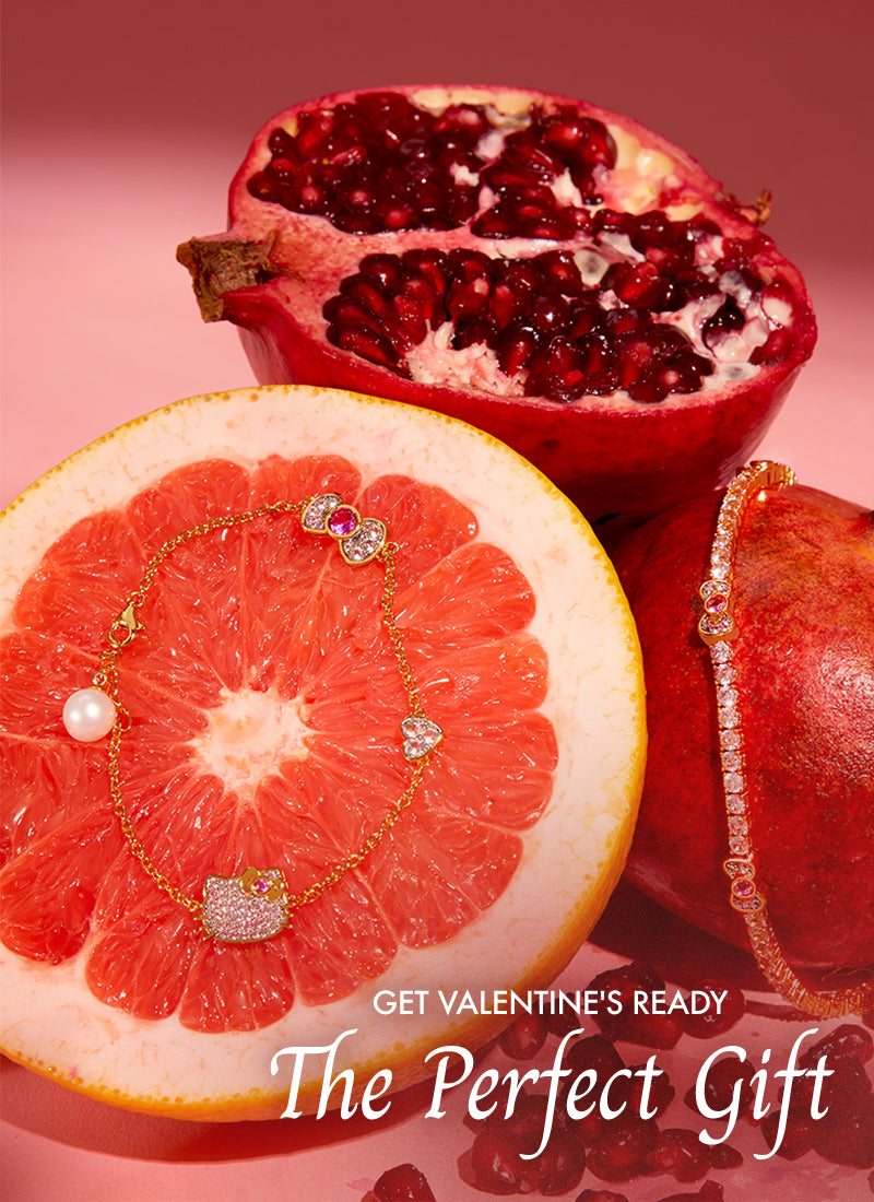Jewelry on a sliced grapefruit with pomegranate, promoting Valentine's Day gift ideas.