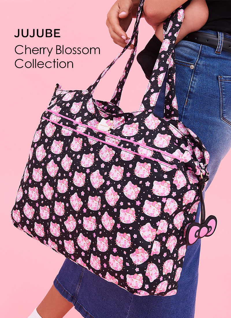 Person holding a JuJube bag with cherry blossom pattern against a pink background