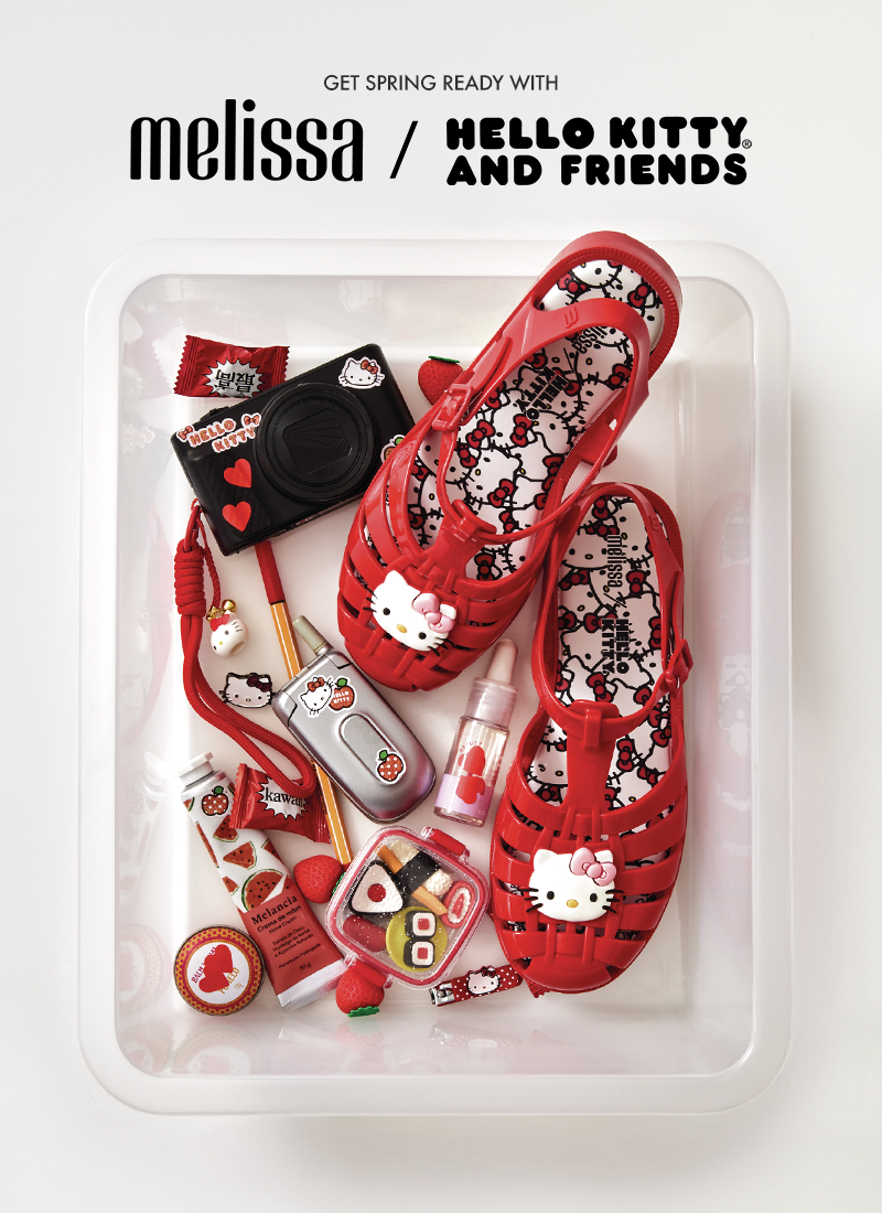 Red sandals with Hello Kitty design on a white tray, surrounded by small accessories, with 'Melissa' branding.
